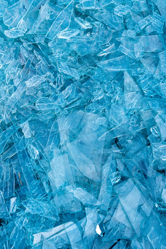 Vibrant close-up image of shattered blue glass with sharp edges and intricate patterns.