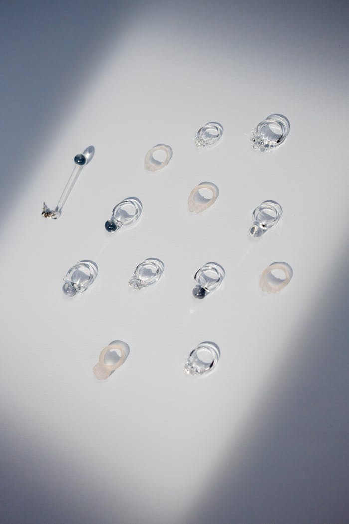 Collection of clear glass jewelry artfully arranged on a white background with soft lighting.