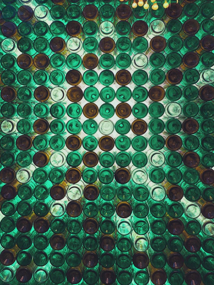 Vibrant artistic display of green and brown glass bottles creating an abstract pattern viewed from below.