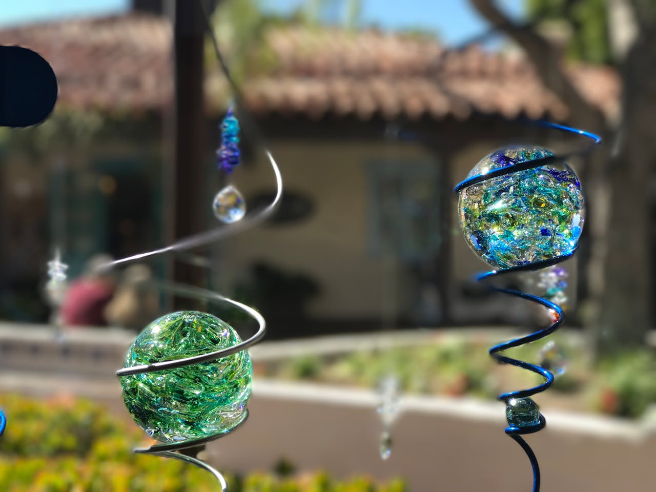 Vibrant glass orbs with spirals hanging outdoors, captured on a sunny day.